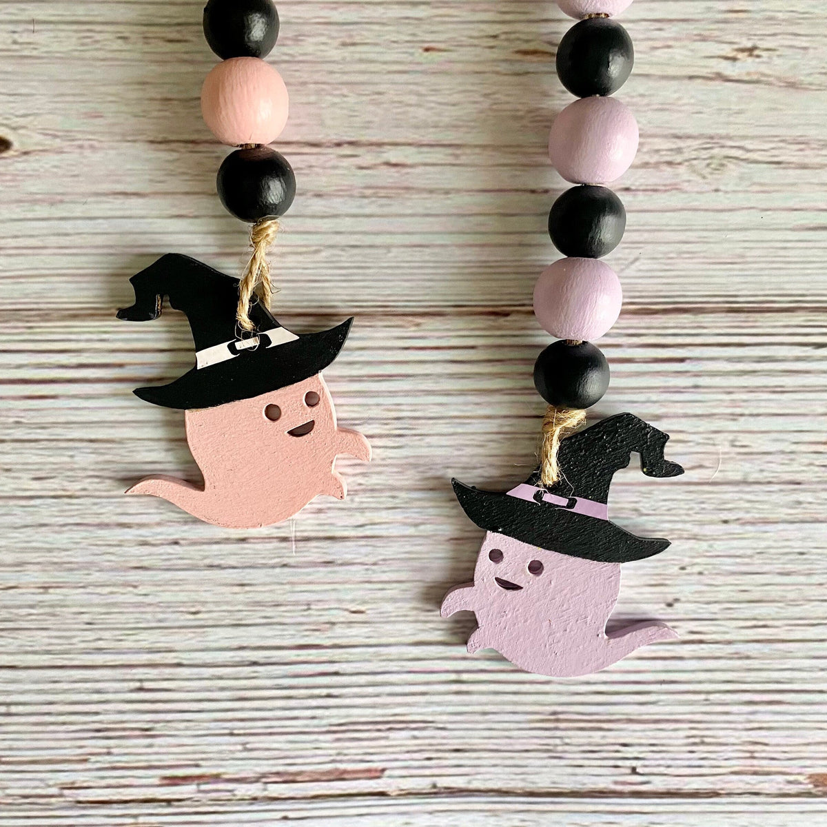 ghosts in witch hats on a beaded garland one is pink one is lavender