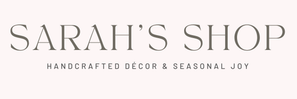 A minimalist logo banner for 'Sarah's Shop' featuring the text 'SARAH'S SHOP' in a large, elegant serif font, with the tagline 'HANDCRAFTED DÉCOR & SEASONAL JOY' written below in a smaller sans-serif font, set against a solid pale pink background.