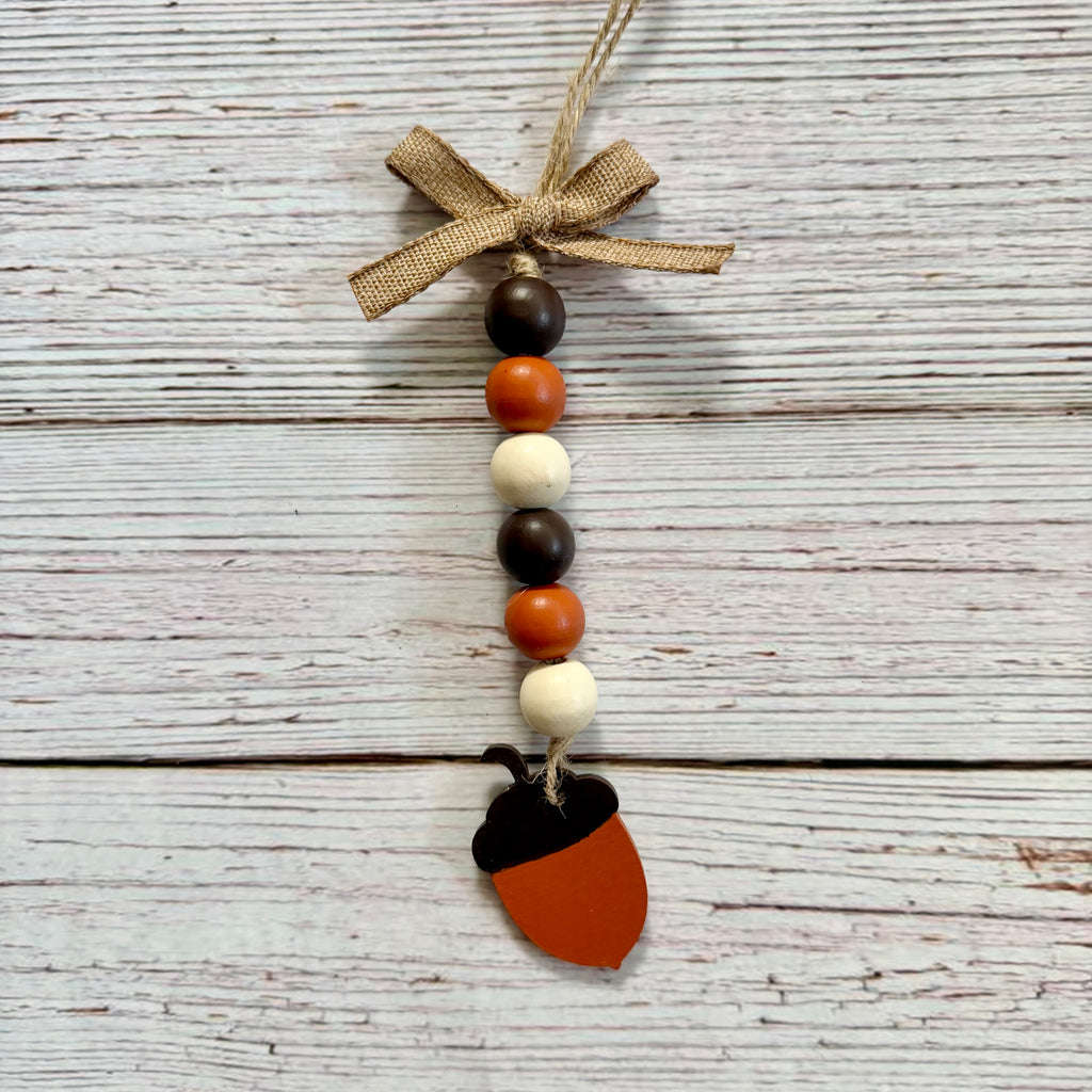 Acorn-shaped beaded hanging ornament with a burlap bow