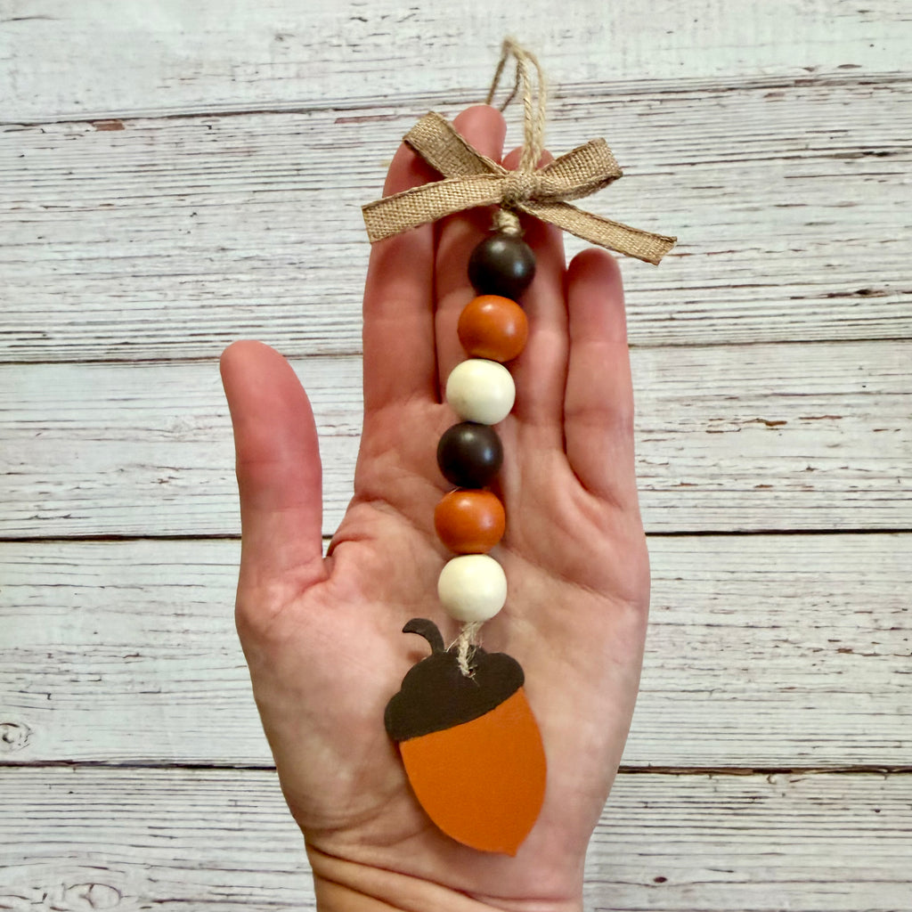 Hand holding a bead garland with an acorn tag