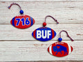 Three wooden football-shaped ornaments in red, white, and blue are arranged on a whitewashed wood background. One ornament shows the number 716, another says BUF, and the third features a buffalo silhouette.
