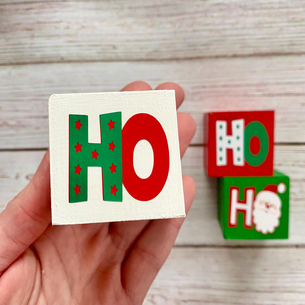 Hand holding white wood block with red and white Ho graphic 