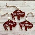 Three buffalo-shaped wooden ornaments with 'TOUCHDOWN' text and white beads, displayed on a whitewashed wood background.