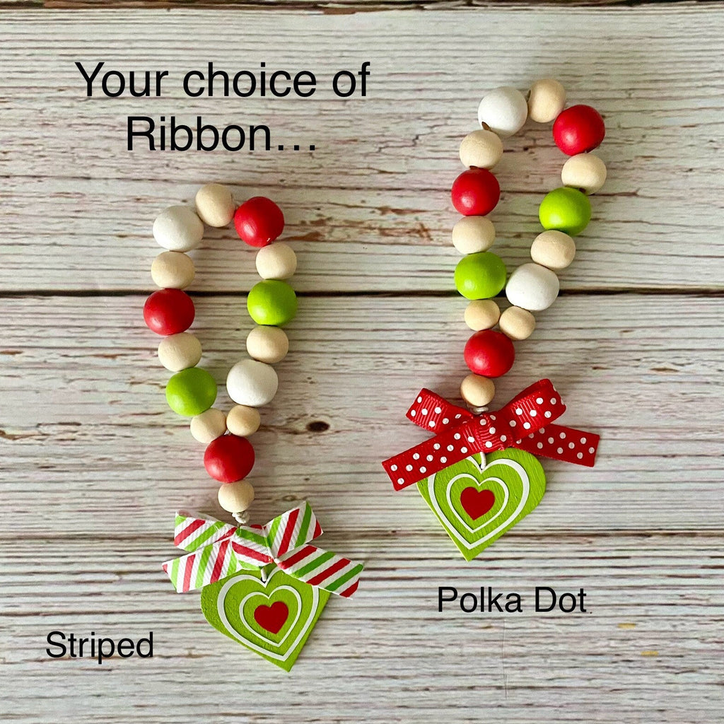 Two beaded heart-shaped hanging ornaments displayed on a whitewashed wood background, labeled 'Your choice of Ribbon.